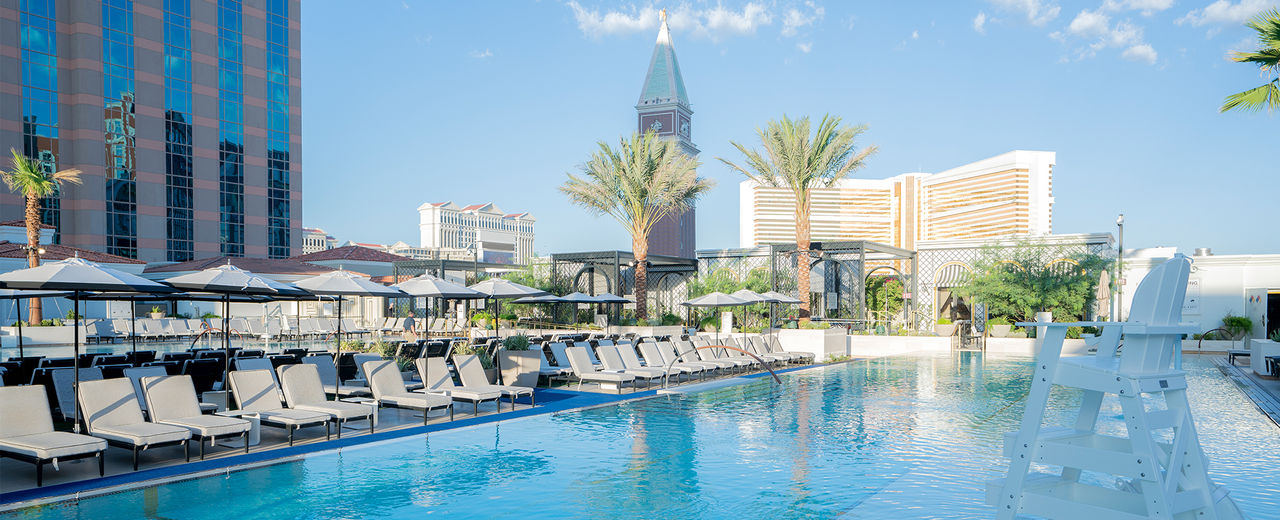 the venetian pool deck, pools, cabanas, daybeds, blue sky, palm trees, campanile tower,